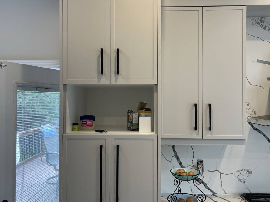 A well-organized kitchen with pull-out drawers, tiered shelves, and labeled containers in cabinets.